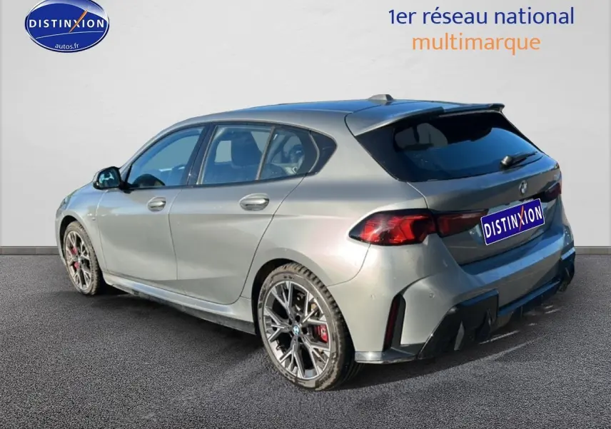 BMW Série 1 118da 2025 gris skyscraper vue 3/4 arrière droit avec jantes bicolores et diffuseur noir.