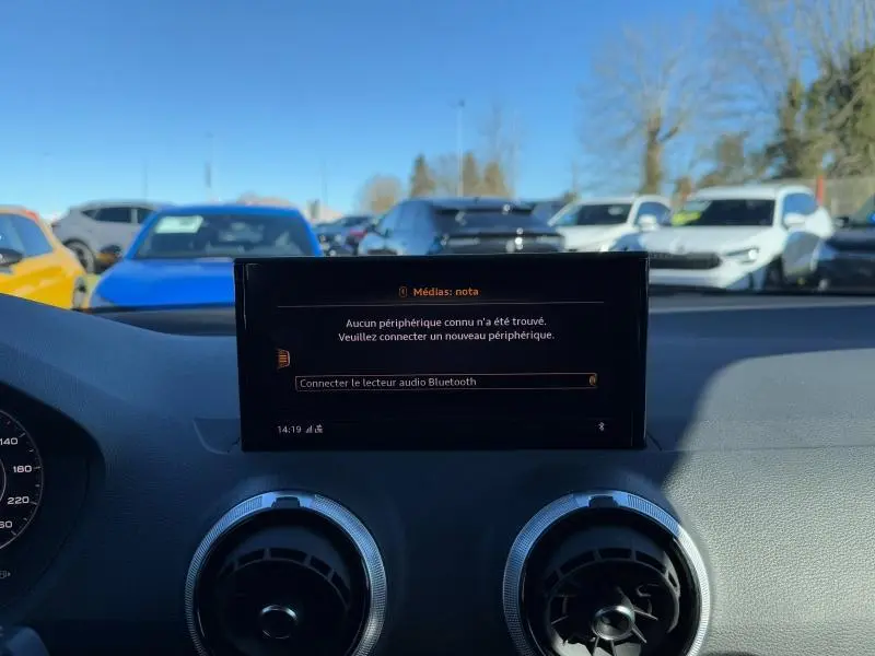 Vue intérieure du tableau de bord de l'Audi Q2 30 TDI 2024 avec écran multimédia et aérateurs ronds, volant cuir visible.
