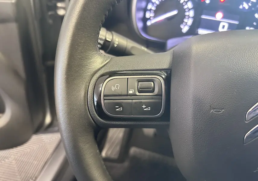 Gros plan sur le volant cuir noir de la Citroën C3 Aircross 2024 avec commandes audio intégrées.