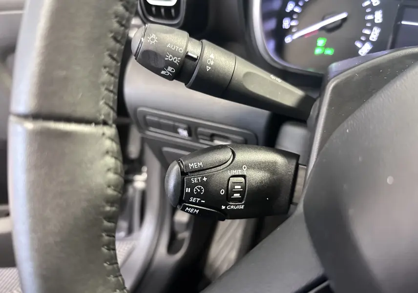 Gros plan sur le volant cuir et les commandes de régulateur de vitesse du Citroën C3 Aircross 2024, intérieur noir.