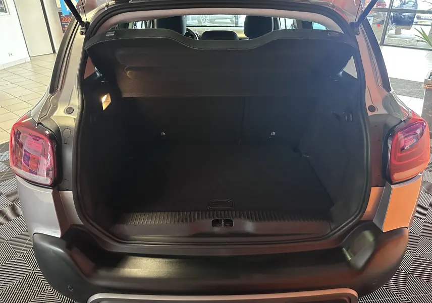 Coffre ouvert vu de l'arrière d'un Citroën C3 Aircross gris Artense 2024, intérieur spacieux et bien éclairé.