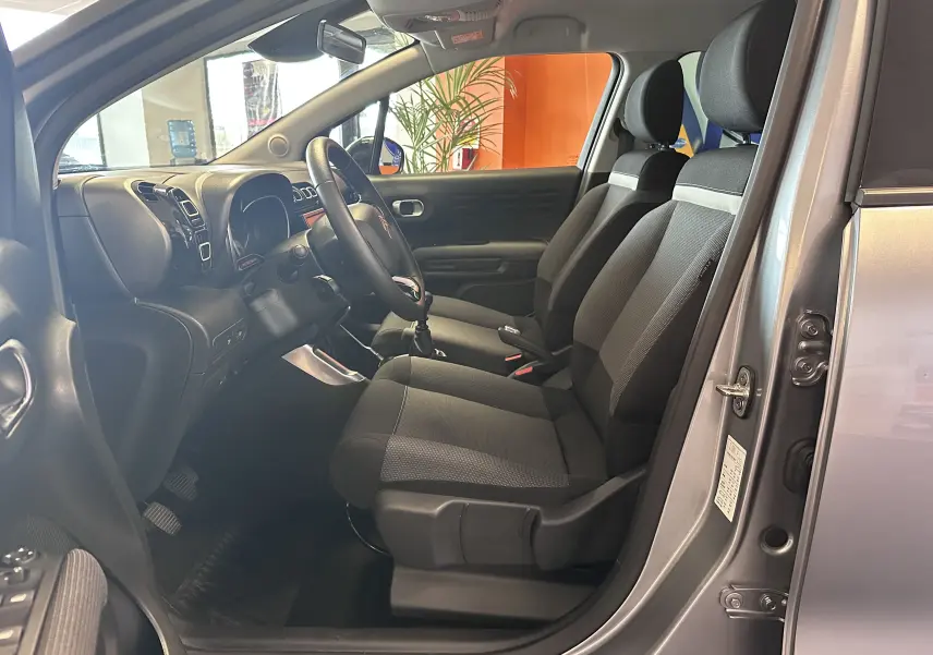 Vue intérieure côté conducteur de la Citroën C3 Aircross gris Artense, sièges tissu gris et volant cuir.