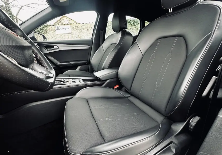 Vue intérieure côté conducteur du CUPRA Formentor 2.0 TDI 2025, sièges sports bimatière noirs avec surpiqûres blanches.