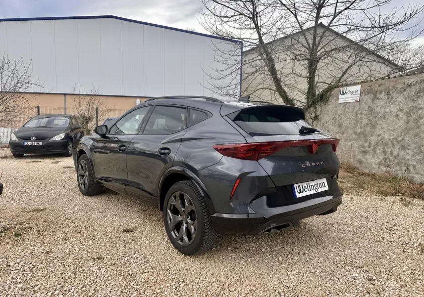 Vue 3/4 arrière droite d'un CUPRA Formentor gris 2025 avec feux arrière triangulaires et jantes noires distinctives.