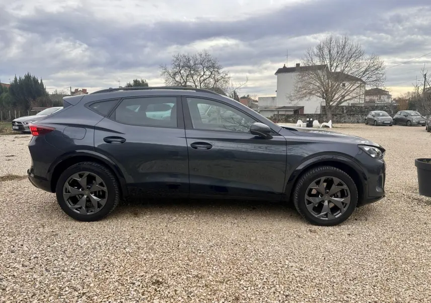 Vue de profil côté gauche d'un CUPRA Formentor gris 2025 avec jantes noires et toit ouvrant.