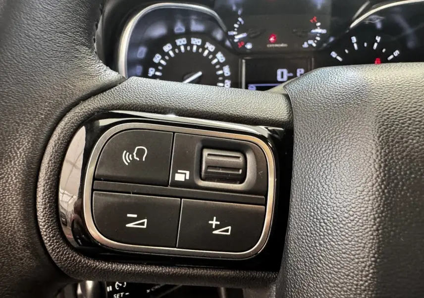 Gros plan sur le volant cuir multifonctions côté gauche de la Citroën C3 gris foncé avec commandes vocales et volume.