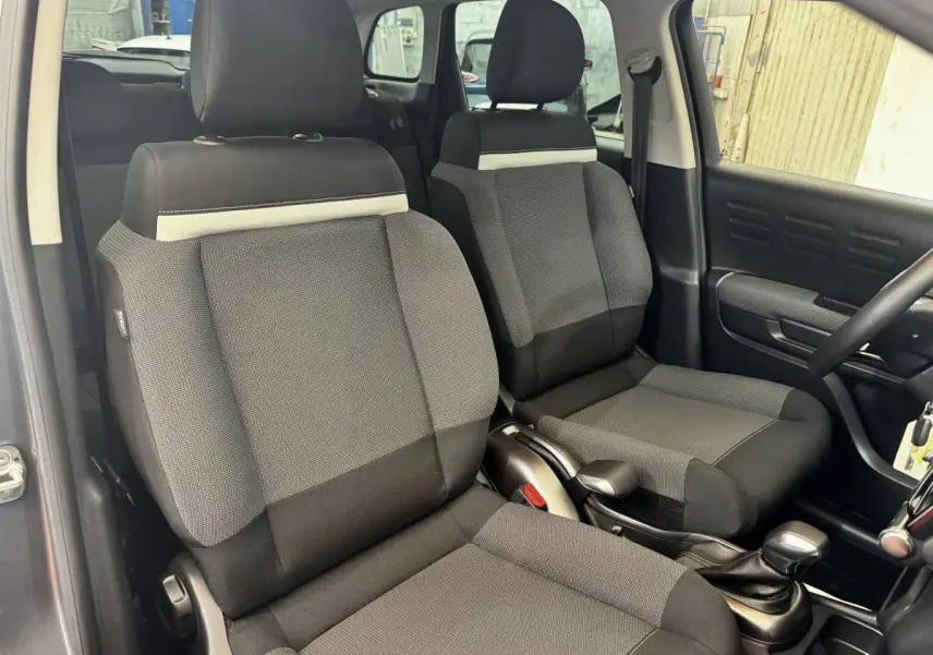 Vue intérieure côté avant droit montrant les sièges tissu gris foncé et noir de la Citroën C3 2019 Shine.