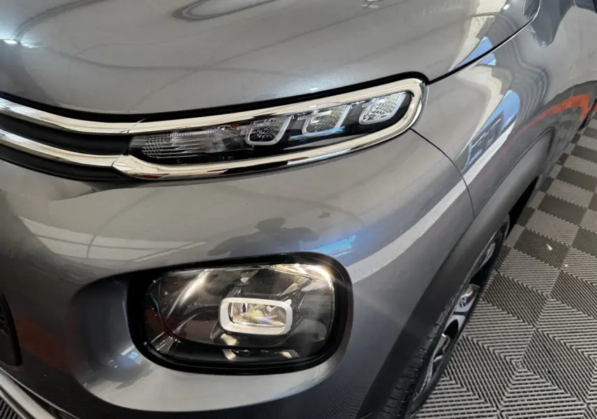 Gros plan sur le phare avant droit gris foncé d’une Citroën C3 PureTech 110 Shine, soulignant ses feux LED distinctifs.