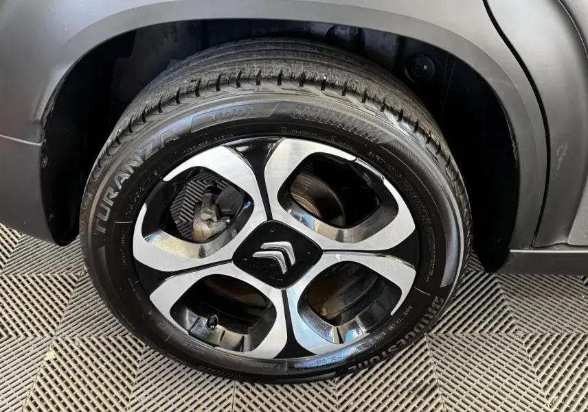Gros plan sur la roue avant droite d'une Citroën C3 gris foncé avec jante alliage bicolore et logo Citroën central.