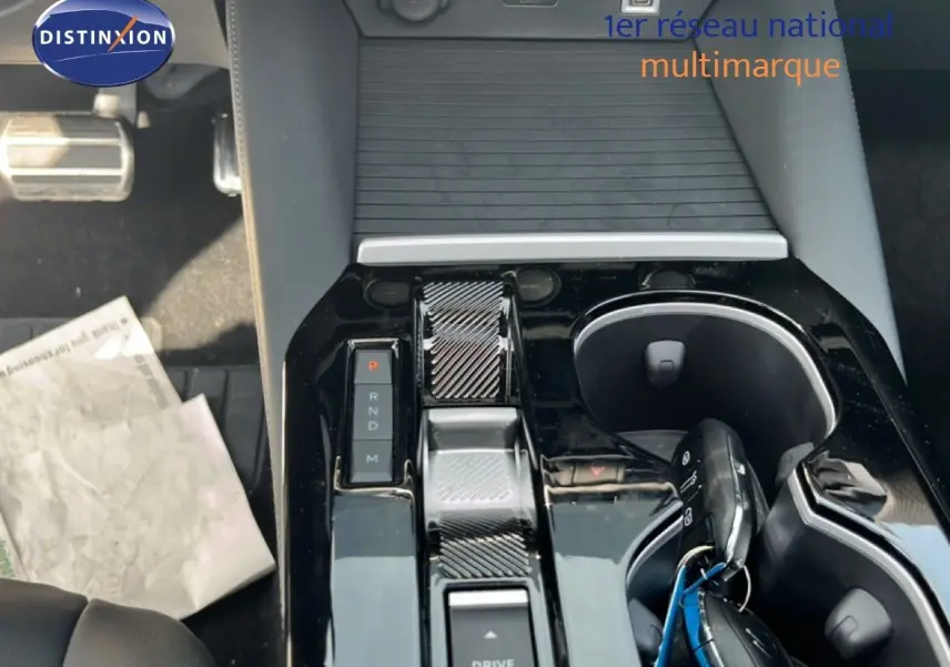 Vue rapprochée de la console centrale noire brillante de la Citroën C5 X 2023, avec levier de vitesses et porte-gobelets.