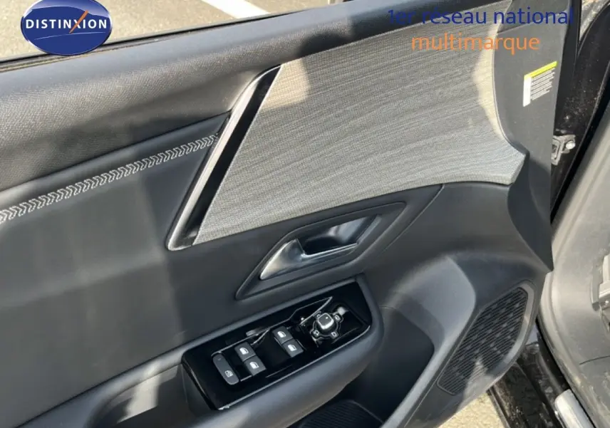 Détail de la porte avant gauche noire métal du Citroën C5 X 2023 avec commandes de vitres et insert tissu gris.