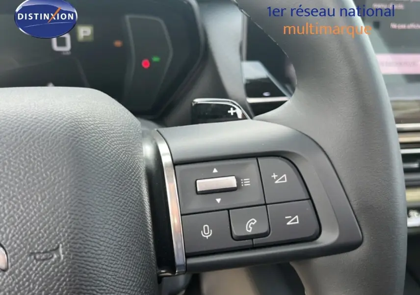 Gros plan sur les commandes au volant du Citroën C5 X 2023 noir métal, avec boutons de volume et téléphone visibles.