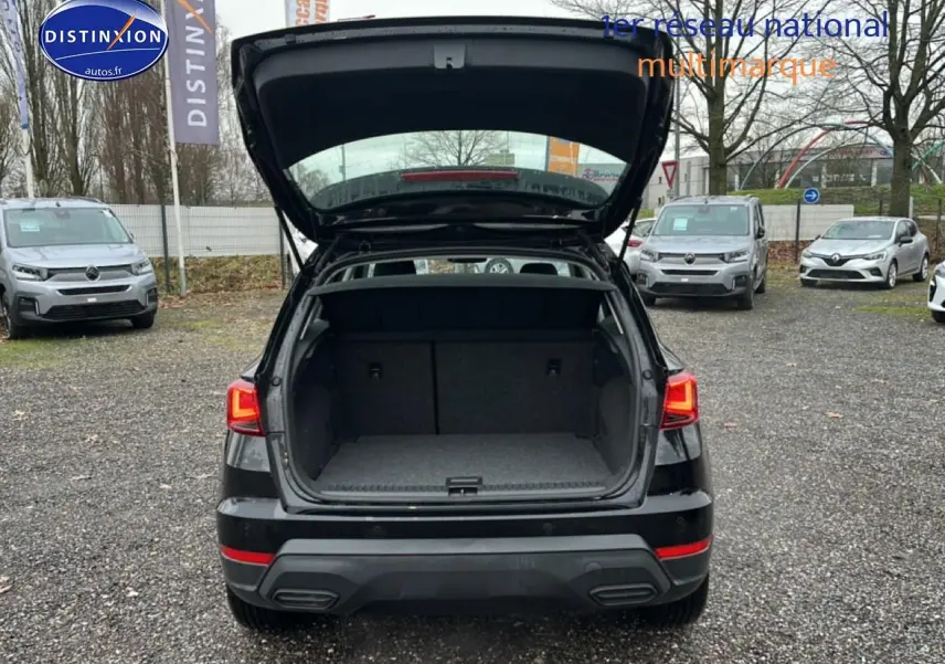 Vue arrière d'un SEAT Arona noir minuit 2025 avec coffre ouvert sur un parking extérieur.