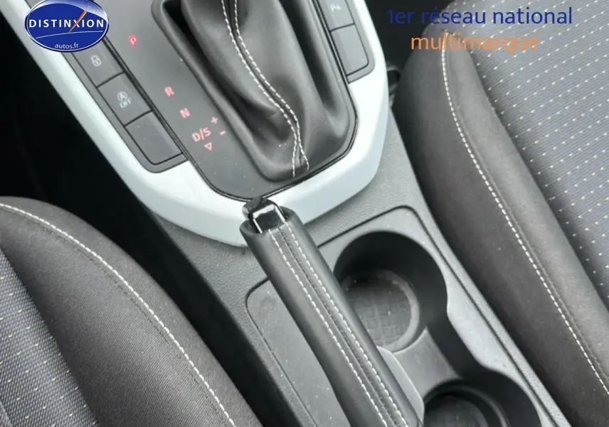 Vue rapprochée de la console centrale avec levier de frein à main cuir noir et sièges tissu gris du SEAT Arona 2025.