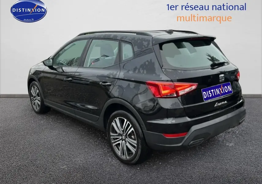 Vue 3/4 arrière droite d'un SEAT Arona noir minuit avec jantes 17 pouces et signature manuscrite sur hayon.
