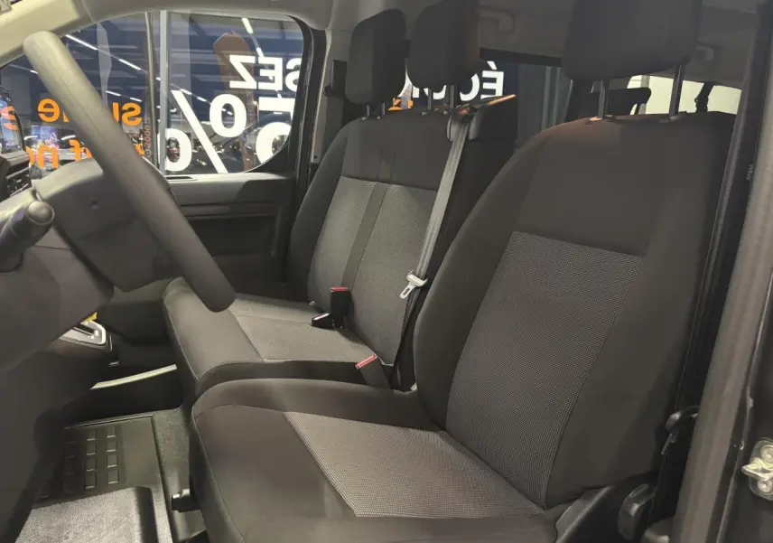 Vue intérieure côté conducteur du FIAT Scudo Fourgon gris foncé, montrant les sièges tissu bi-ton noir et gris.