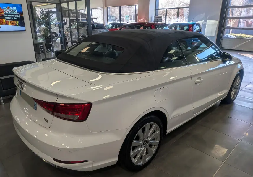 Audi A3 Cabriolet blanc vue 3/4 arrière droit avec capote noire déployée en intérieur showroom.