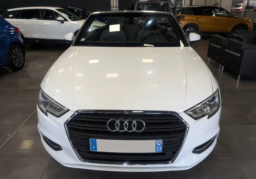 Audi A3 Cabriolet blanc vue 3/4 avant droit, capote ouverte, intérieur cuir noir, en showroom.