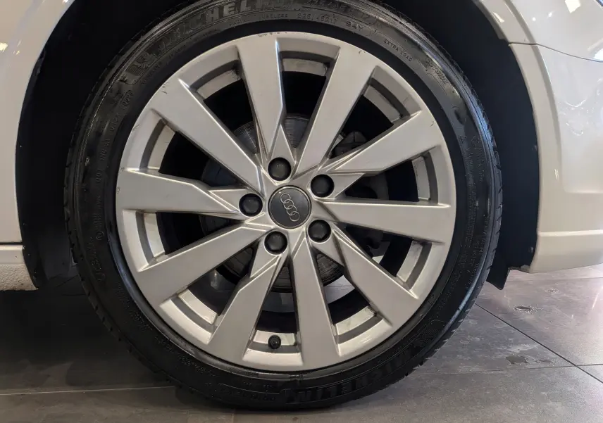 Gros plan sur la jante alliage argentée de l'Audi A3 Cabriolet blanc, mettant en valeur le logo Audi central.