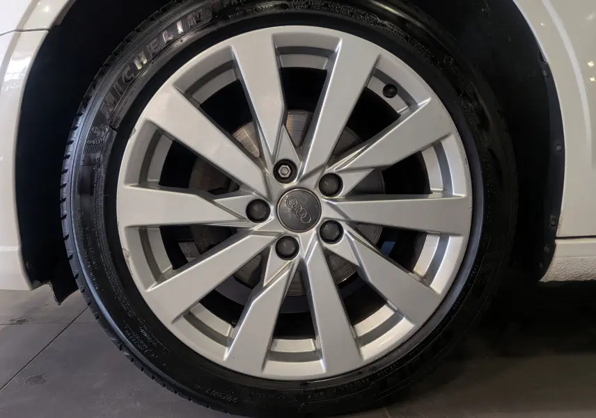 Gros plan sur la jante alliage argentée de l'Audi A3 Cabriolet blanc, mettant en valeur le logo Audi au centre.