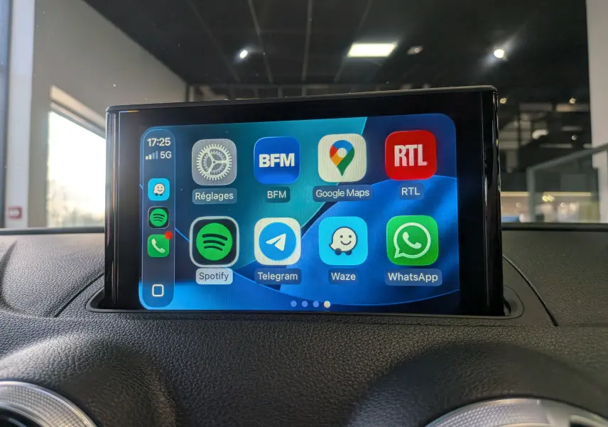 Écran tactile central affichant des applications connectées dans l'habitacle d'une Audi A3 Cabriolet blanc, vue de face.