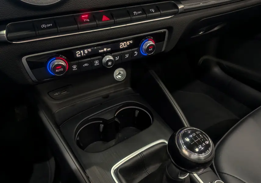 Vue rapprochée de la console centrale noire de l'Audi A3 Cabriolet 2017 avec boîte manuelle et commandes de climatisation digitales.
