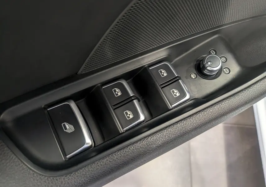 Gros plan sur les commandes des vitres électriques et réglage des rétroviseurs côté conducteur d'une Audi A3 Cabriolet blanc 2017.