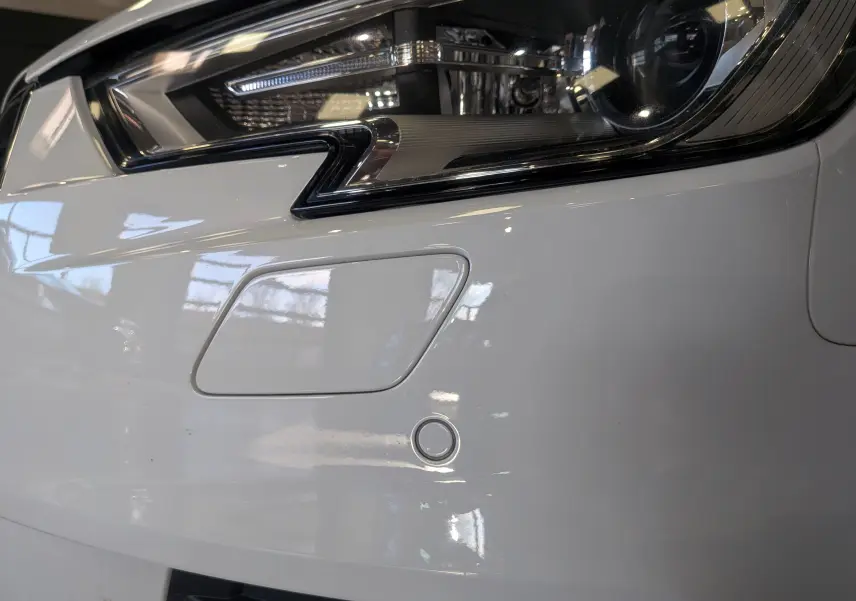 Gros plan sur le phare avant droit blanc d'une Audi A3 Cabriolet 2017 avec capteur de stationnement intégré.