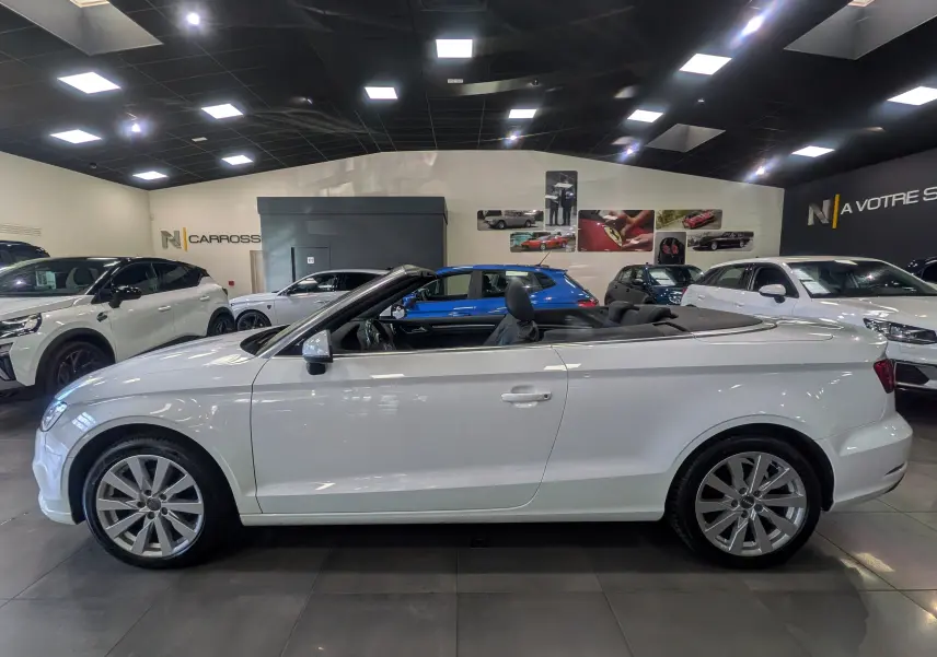 Audi A3 Cabriolet blanc vue de profil côté gauche, capote ouverte, intérieur noir visible en showroom.