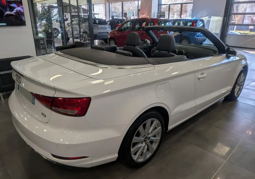 Audi A3 Cabriolet blanc vue 3/4 arrière droit, toit ouvert, intérieur noir, en showroom lumineux.