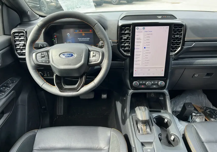Vue intérieure frontale du Ford Ranger 2025 blanc glacier, montrant le volant cuir multifonctions et l’écran tactile vertical central.