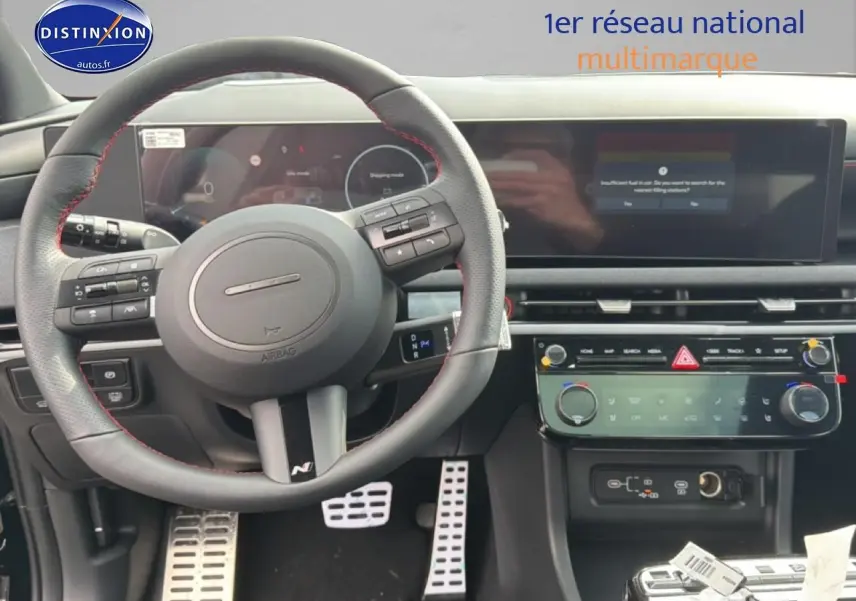 Vue intérieure centrée sur le volant cuir noir avec surpiqûres rouges et tableau de bord numérique du Hyundai Tucson 2026.
