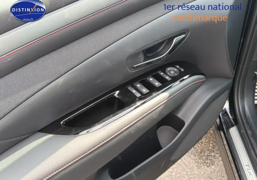 Gros plan sur la porte avant gauche noire du Hyundai Tucson 2026, avec commandes électriques et surpiqûres rouges.