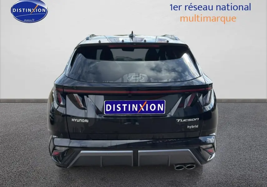 Vue arrière d'un Hyundai Tucson noir hybride avec feux arrière LED et double sortie d'échappement chromée.