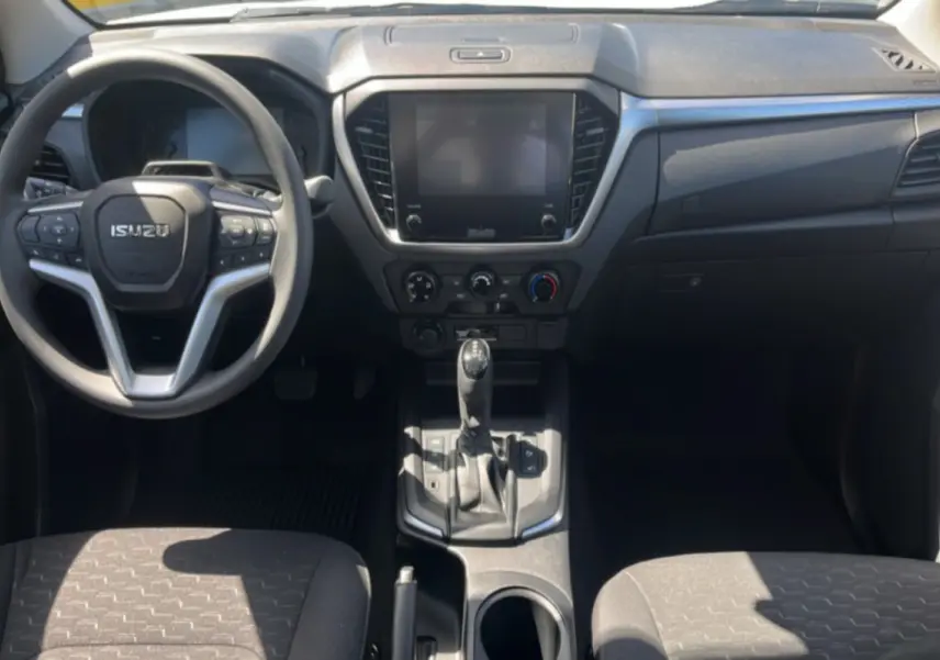 Vue intérieure frontale de l'Isuzu D-MAX 2026 avec tableau de bord noir et écran tactile central.