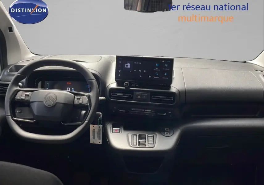 Vue intérieure frontale du poste de conduite du Citroën Berlingo 2026, tableau de bord et volant noirs avec écran tactile central.