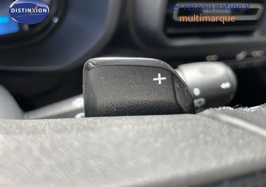 Gros plan sur la palette de changement de vitesse "+" au volant du Citroën Berlingo 2026, intérieur noir.