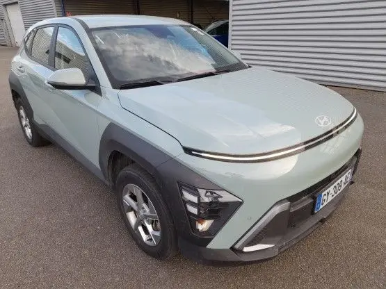 Vue 3/4 avant d’un Hyundai Kona 2024 Mirage Green avec phares LED et protections noires autour des roues.