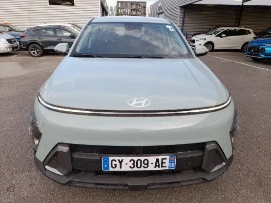 Vue frontale d'un Hyundai Kona 2024 Mirage Green avec calandre épurée et phares LED fins en parking.