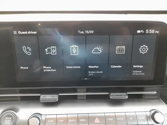 Écran tactile central de la Hyundai Kona 2024 affichant les menus téléphone, météo, calendrier et réglages, intérieur noir.