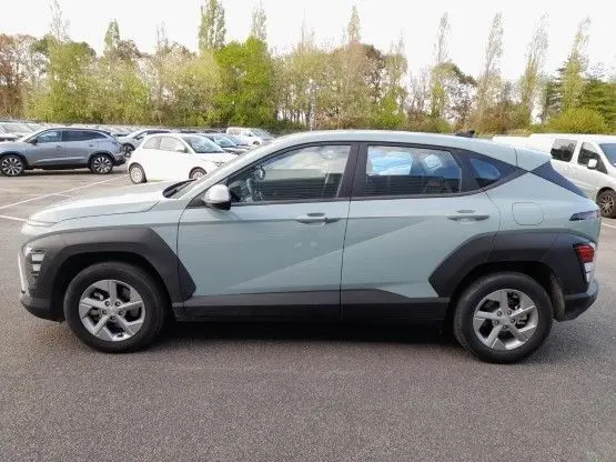 Vue de profil côté gauche d'un Hyundai Kona 2024 hybride en couleur Mirage Green avec protections noires sur les ailes.