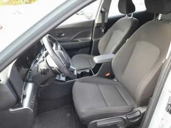 Vue intérieure côté conducteur du Hyundai Kona 2024, sièges tissu gris foncé et volant cuir multifonction.