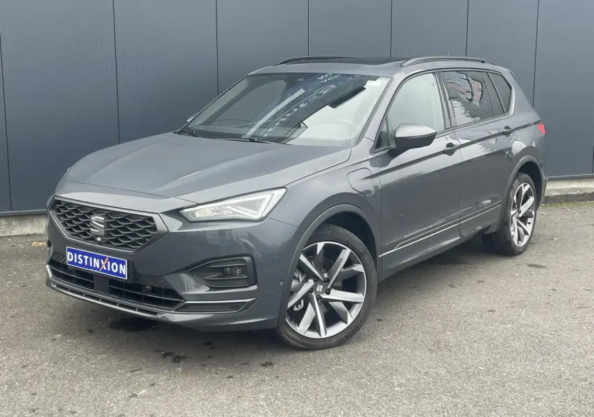 SEAT Tarraco gris dauphin en 3/4 avant droit, toit ouvrant panoramique et jantes alliage 20 pouces visibles.