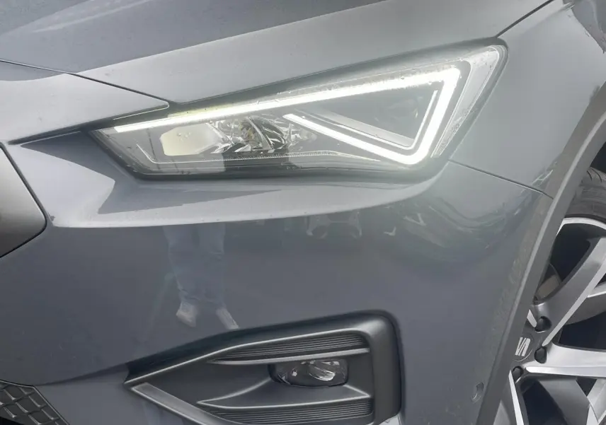 Gros plan sur le phare avant droit allumé et la jante alliage 20 pouces du SEAT Tarraco gris Dauphin.