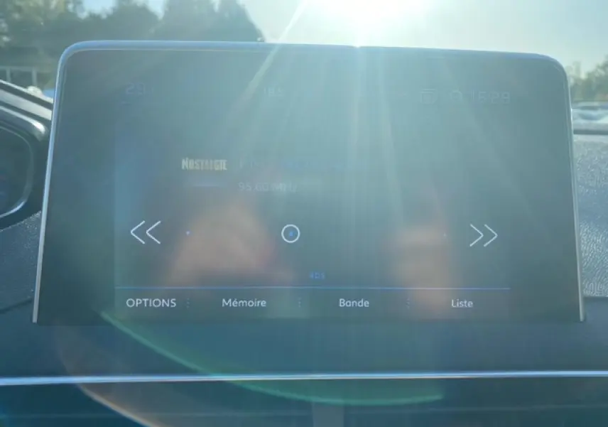 Écran tactile central du Peugeot 3008 2018 avec affichage radio, lumière du soleil et reflet visibles.