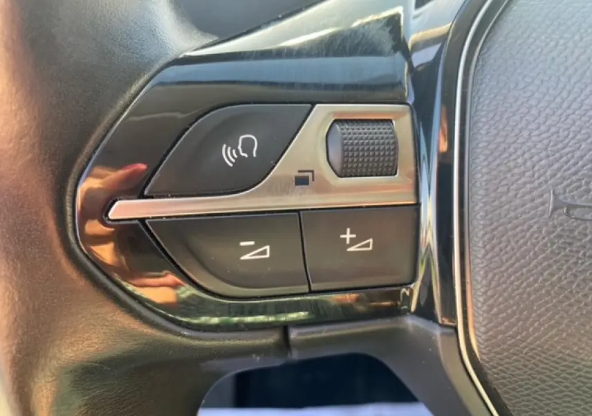 Gros plan sur les commandes de volume et voix du volant noir du Peugeot 3008 beige clair, version 2018.