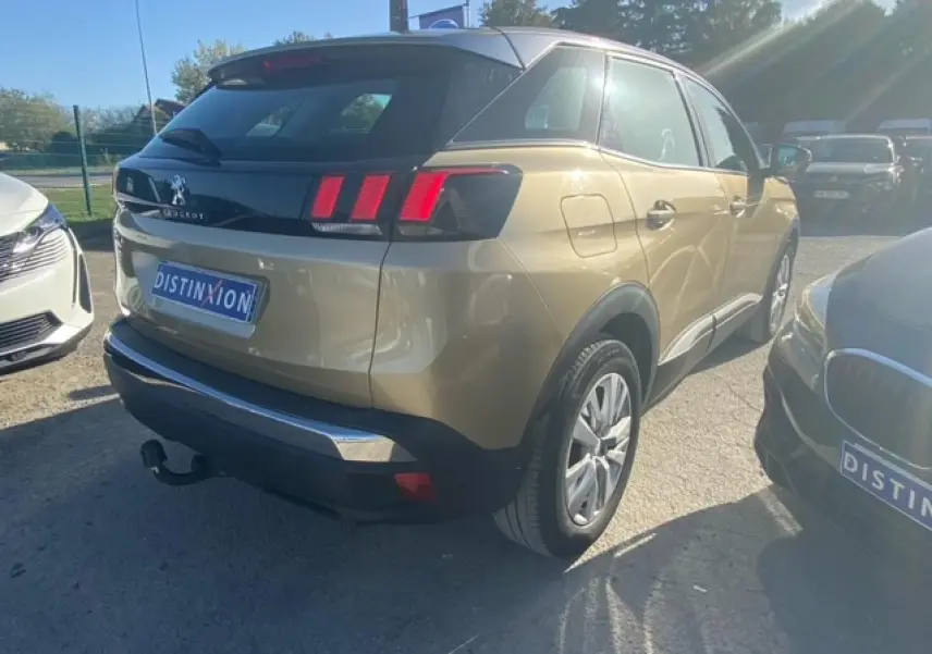 Vue 3/4 arrière droite d'un Peugeot 3008 beige clair avec attelage et jantes alliage 17 pouces, stationné en extérieur.