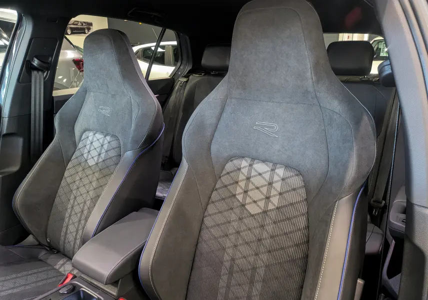 Vue intérieure rapprochée des sièges avant gris avec surpiqûres bleues et logo R sur une Volkswagen Golf VIII R-Line.