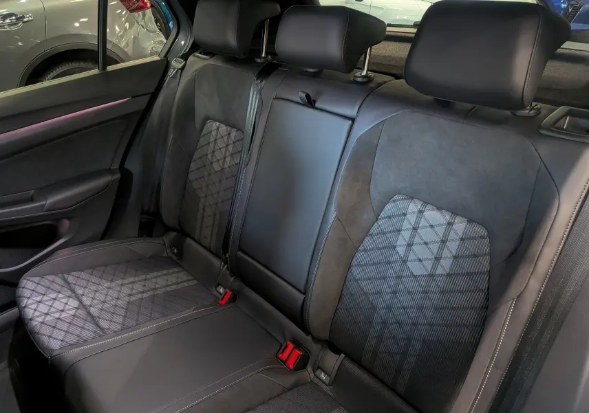 Vue intérieure des sièges arrière en tissu et cuir noir avec motifs géométriques dans une Volkswagen Golf VIII gris Urano.