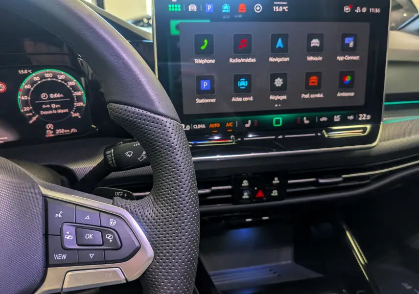 Vue intérieure centrée sur le volant et l'écran tactile du tableau de bord de la Volkswagen Golf VIII gris Urano.